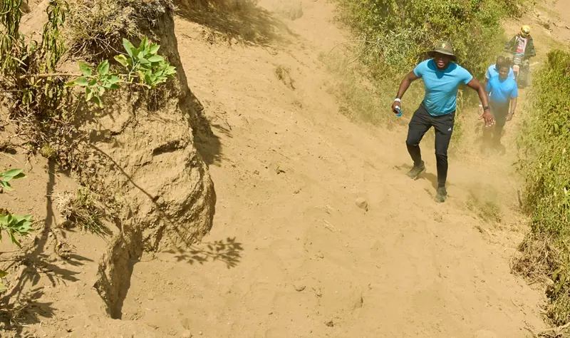 Runners climbing a steep sandy trail during an Ibiza Fun Run event in Naivasha