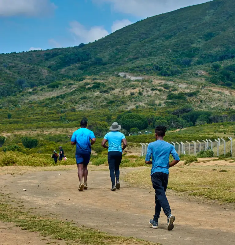 Runners in event tees heading toward green hills on a trail run