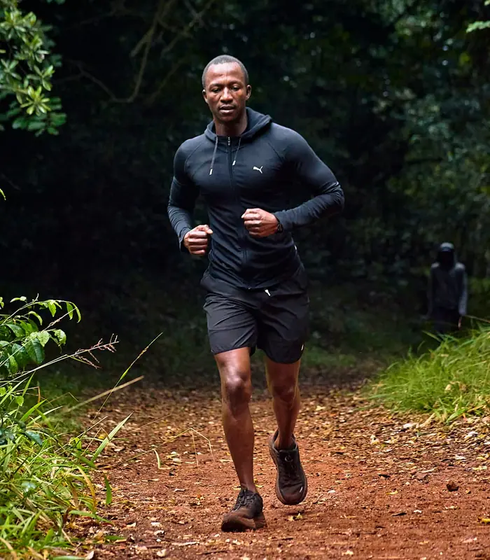 A runner pushing through a shaded forest section